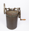 A rusted cylindrical metal container with gears and a handle on the lid.