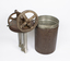 A rusted metal container and a lid with gears and a whisk-like structure reaching downwards.