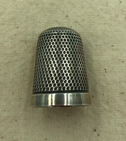 Silver thimble with honeycomb pattern and plain band on the rim.