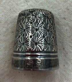 Silver thimble with dense floral design on side and wide band around rim.