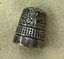 Silver thimble with floral design, decorative bands and manufacturer's imprint.