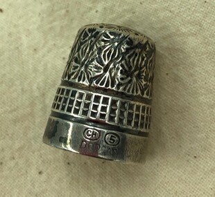 Silver thimble with floral design, decorative bands and manufacturer's imprint.