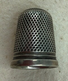 Decorative silver thimble with honeycomb pattern on side.