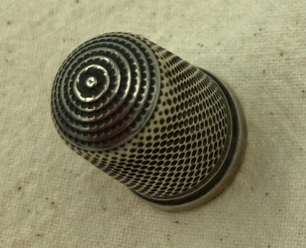 Silver thimble with spiral pattern on the top.