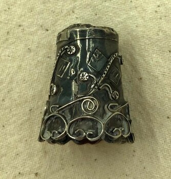 Ornate decorations on the side of silver thimble.