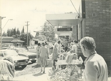 A busy footpath lined with market stands.
