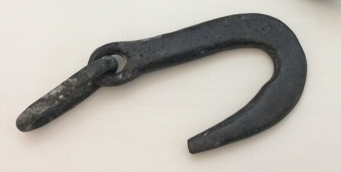 A large iron hook with a smaller loop through the hook's eye.