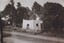 A sepia photograph of a brick or stone and wood building by a road.