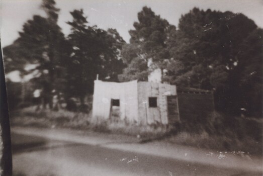 A sepia photograph of a brick or stone and wood building by a road.
