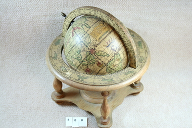 Globe on decorative wooden stand.