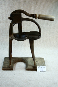 Iron citrus squeezer mounted on stand.