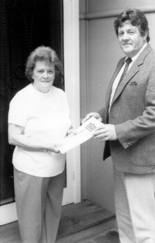 A man in a suit presenting an award to a woman more casually dressed.