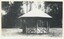 A black and white photograph of a rotunda on flat open ground, with trees in the background.