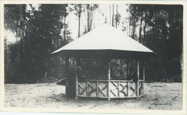 A black and white photograph of a rotunda on flat open ground, with trees in the background.