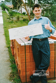 Photograph, Simon Miller holding up a sign protesting at the construction of speed humps, 1991