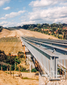 Photograph, Looking east across the new bridge construction across the Plenty River from the western side up to the new roundabout at Civic Drive; Greensborough Bypass construction, c.1986, 1986c
