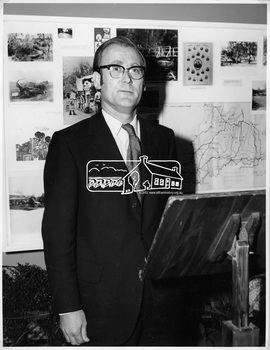 Man dressed in suit with glasses standing in front of a podium