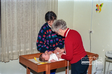 Photograph, Believed to be Sister Alma Brown checking a baby at the Maternal and Child Health Centre, War Memorial Hall, 905 Main Road, Eltham, 1989