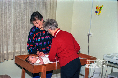 Photograph, Believed to be Sister Alma Brown checking a baby at the Maternal and Child Health Centre, War Memorial Hall, 905 Main Road, Eltham, 1989