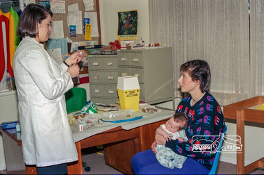 Photograph, Dianne Yans about to administer a vaccine shot to a young baby at the Maternal and Child Health Centre, War Memorial Hall, 905 Main Road, Eltham, 1989, 1989