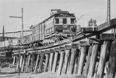 Photograph, George Coop, E1106, an E-class electric locomotive hauling freight cars across the Eltham Railway Trestle Bridge, c.1981, 1981