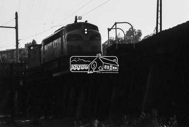 Photograph, A Melbourne bound B Class Diesel-Electric Locomotive silhouetted as it crosses the Eltham Railway Trestle Bridge, c.1983, 1983