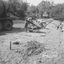 Wet concrete slides out of a concrete truck along dug out footings where men work to spread the concrete