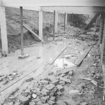Water accumulates with timber footings and brick rubble beisde the newly constructed house, beneath the  pagola.