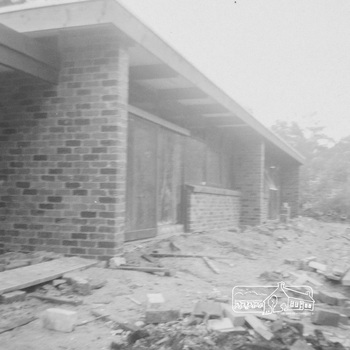 Newly constructed brick house with flat roof and building rubble outside