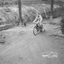 A boy rides a bike with training wheels on a hard dirt surface