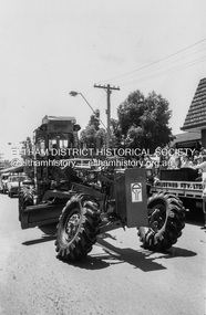 Photograph - Black and White Print, The Shire of Eltham's new Komatsu tandem drive grader participates in the Eltham Festival Grand Parade along Main Road, c.1978