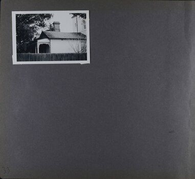 One photo on page - side view of an old house and part of tower taken over a large wooden fence