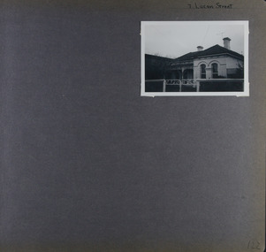 1 photo - old house with verandah and arched windows at front behind its low front gates.