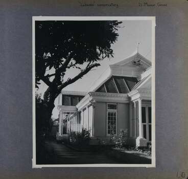 1 photo - looking down the side of a formal-looking old building with long windows and a side porch.