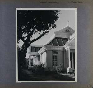 1 photo - looking down the side of a formal-looking old building with long windows and a side porch.