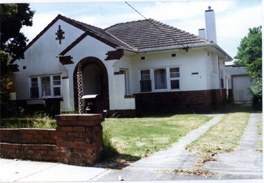 White house with brown brick features and a brown brick fence.  Down the drive is a rear white garage