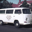 Meals on Wheels delivery van with driver in front of red brick house and white picket fence.