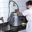 Women in an apron operating a commercial potato processing machine.