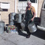 Worker carrying round aluminium food containers.