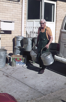 Worker carrying round aluminium food containers.