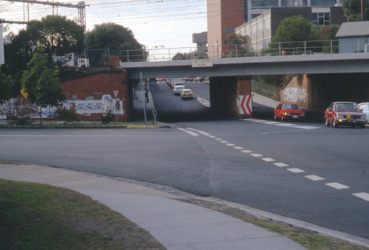 Railway underpass with two red cars in the foreground.
