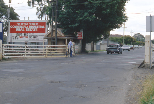 A man closing gates at a railway crossing.