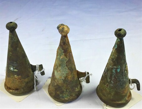 3 metal candle snuffers showing corrosion and encrustation.