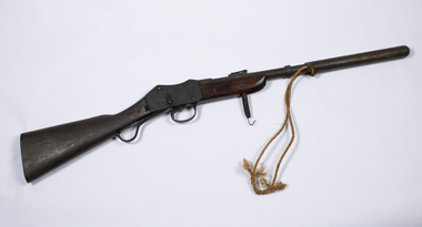 A metal breech loading gun with wooden stock showing locking spring  and rope attached to launch canaster.