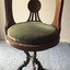 Front and top views of saloon swivel chair from the SS Edina. One piece cast metal base with three legs connected in the middle. Green velvet fabric covered cushion on a round timber seat and back