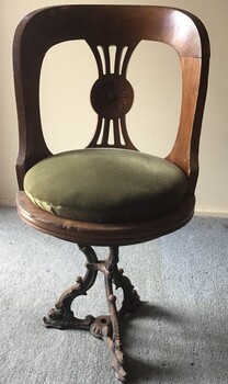 Front and top views of saloon swivel chair from the SS Edina. One piece cast metal base with three legs connected in the middle. Green velvet fabric covered cushion on a round timber seat and back