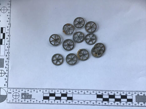 12 miniature toy train wheels of about 12 mm diameter, some with encrustation 
