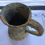 Top and side views of a heavily encrusted pewter tankard with a glass base.