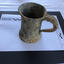 Top and side views of a heavily encrusted pewter tankard with a glass base.