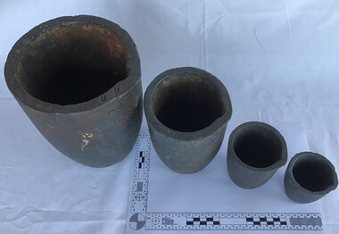 Four carbon crucibles of diminishing sizes used on board ship to melt lead and other repair metals.